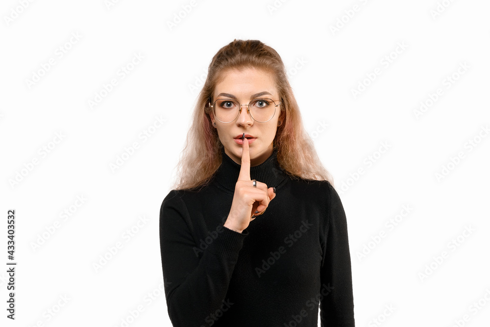 Serious young woman shushing, show taboo hush gesture and frowning, be quiet, standing angry against white background Serious young woman shushing, show taboo hush gesture and frowning, be quiet, standing angry against white background
