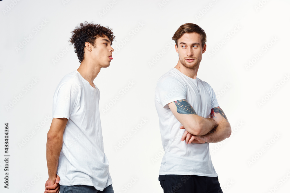 Two cheerful friends in white t-shirts stand side by side cropped view Two cheerful friends in white t-shirts stand side by side cropped view