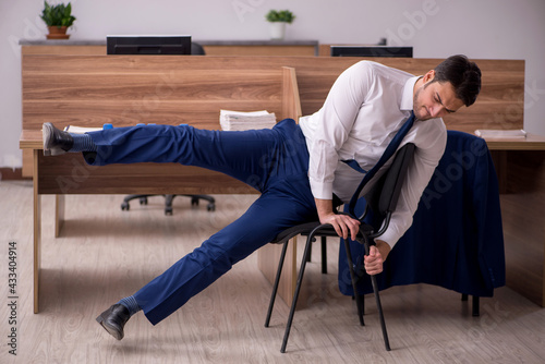 Young businessman employee doing sport exercises at workplace
