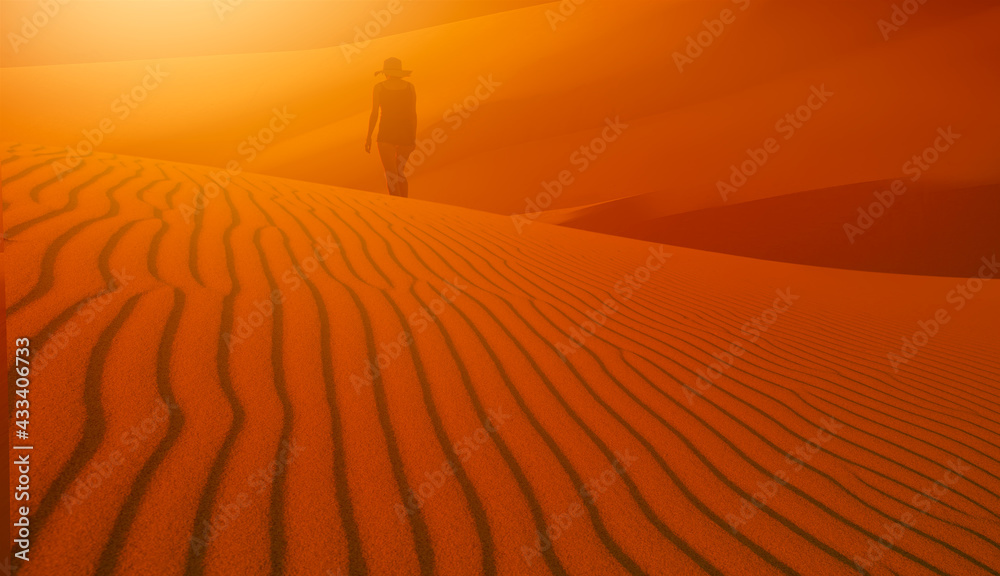 Woman walking alone in the desert with sunset 