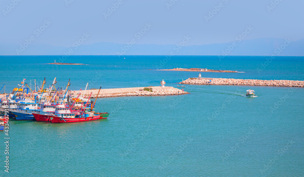 Fishing boats in Karatas Harbour at bright blue sky,  breakwater in the background - Adana, Turkey