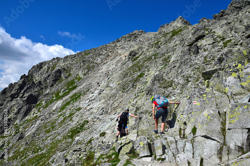 Hikers climbing to the peak of mount Rysy, one of the highest mountains of the High Tatras. Slovakia, Poland.