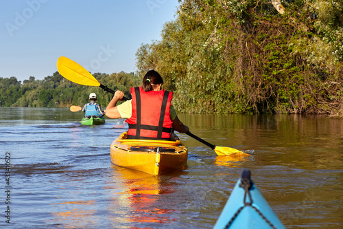 Two women kayaking in the river at summer morning. Back view photo