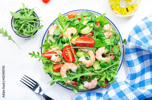 Summer shrimp salad with tomatoes, lettuce, arugula, avocado, cucumber and lemon dressing on white background. Healthy eating, clean food