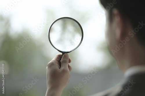 Close up of businessman holding magnifying glass
