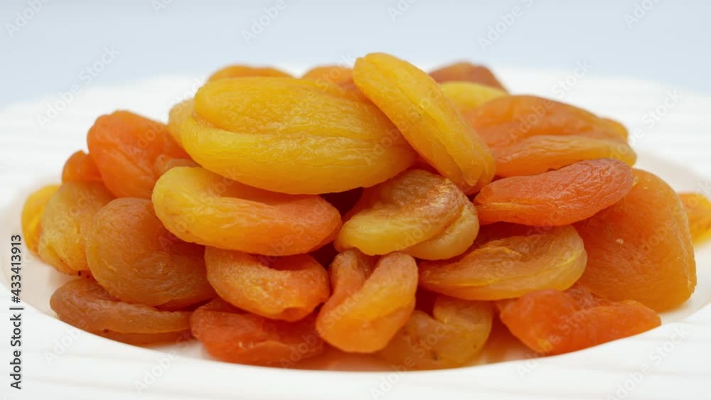 Slowly rotating dried apricots in a plate on a white background Slowly rotating dried apricots in a plate on a white background