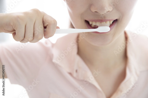 Smiling young woman brushing teeth  cropped