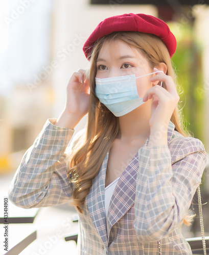 Asian beautiful female who wears suit and red cap is wearing medical face mask in  health care,pollution PM2.5,new normal and coronavirus protection concept. © nut_foto