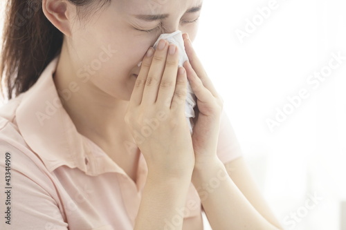 Young woman blowing nose on tissue