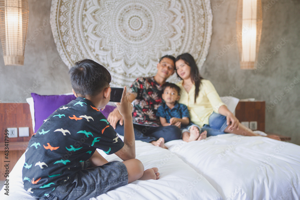 Southeast Asian family spending time at home. Happy Indonesian or malasian parents and children laying in bed having fun together