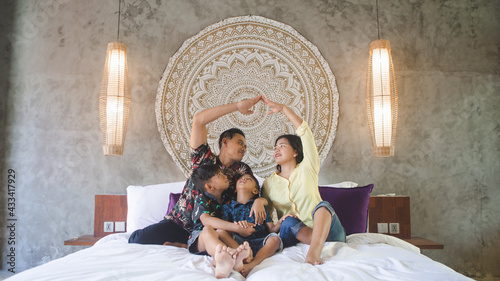 Southeast Asian family spending time at home. Happy Indonesian or malasian parents and children laying in bed having fun together photo