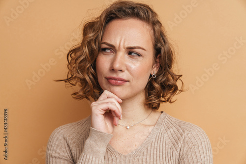 Young ginger puzzled woman frowning and looking aside