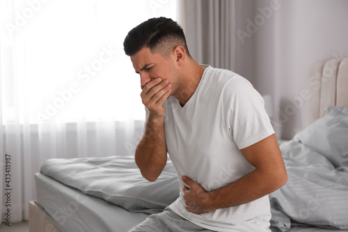 Man suffering from nausea on bed at home. Food poisoning photo