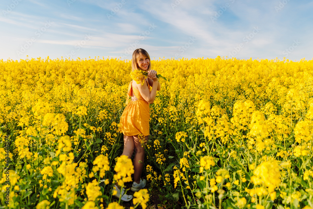 Portrait of attractive woman on blooming rapeseed field with sunset light. Yellow flowers and happy woman Portrait of attractive woman on blooming rapeseed field with sunset light. Yellow flowers and happy woman