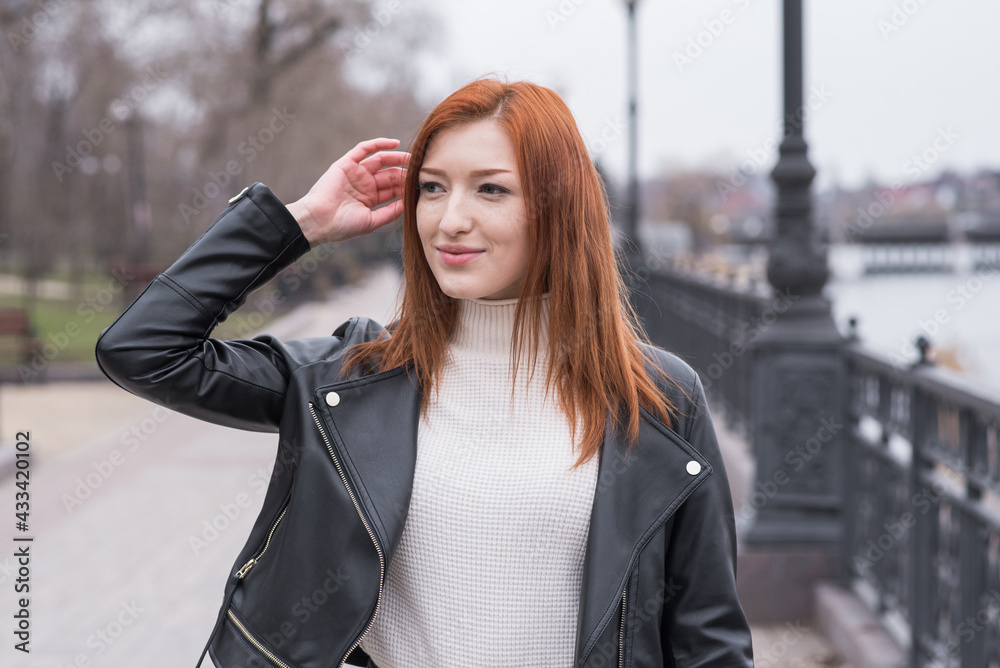 Portrait of a beautiful and positive redhead woman with clothes in grunge style. Posing while walking