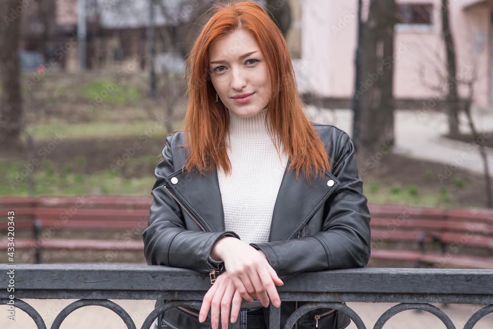 Portrait of a beautiful and positive redhead woman with clothes in grunge style. Posing while walking
