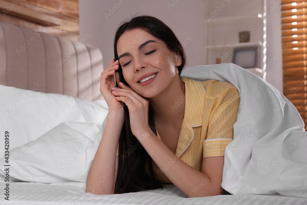 Woman lying in comfortable bed with white linens Woman lying in comfortable bed with white linens