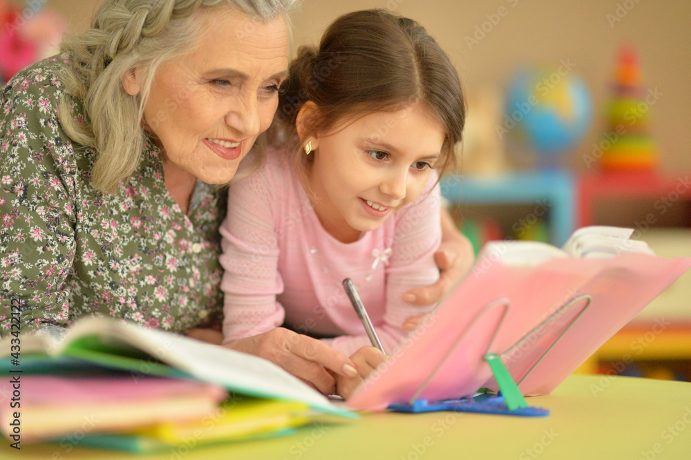 Grandmother with cute little girl doing homework together