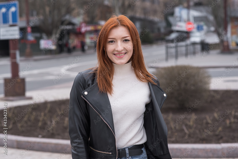 Portrait of a beautiful and positive redhead woman with clothes in grunge style. Posing while walking