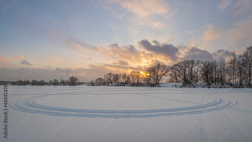 Winter sunrise over the frozen river and bare trees Winter sunrise over the frozen river and bare trees