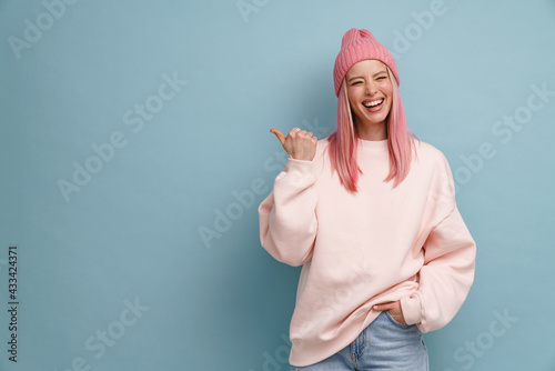 Photos Young woman wearing pink hat laughing and pointing finger aside