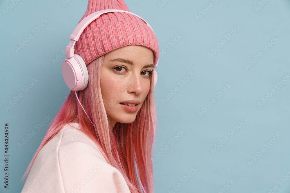 Young white woman wearing pink hat listening music with headphones