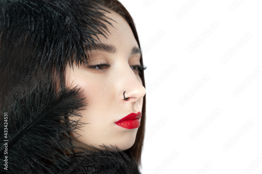 Creative stylish portrait of caucasian model girl with red lips and black feathers around her head, side view. Beauty concept Creative stylish portrait of caucasian model girl with red lips and black feathers around her head, side view. Beauty concept