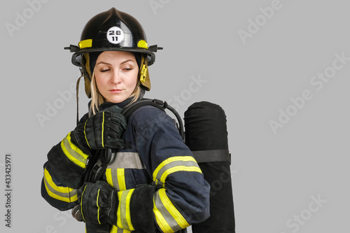  Young caucasian woman in uniform of firefighter posing in profile with Air tank on her back isolated on gray background, copy space © suravikin@gmail.com