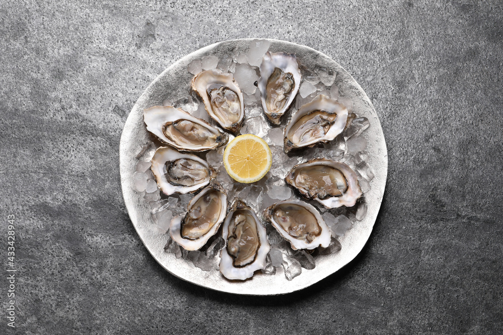 Delicious fresh oysters with lemon on grey table, top view Delicious fresh oysters with lemon on grey table, top view