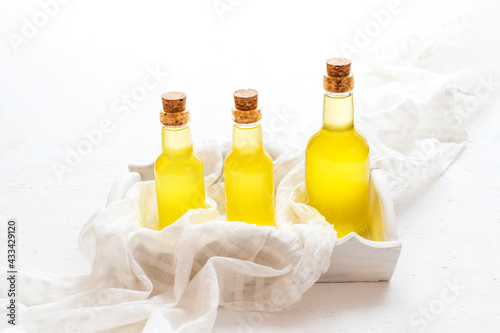 Vegetable oils in a glass bottle on a white tablecloth and a wooden tray and background, cedar, sunflower and almond.