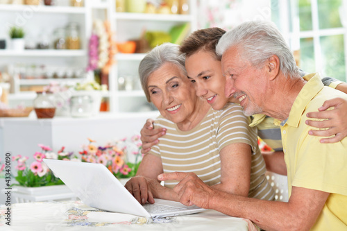 happy senior couple with grandson using  laptop  at home