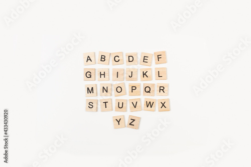 Letra completa de Scrabble alfabeto en mayúscula sobre fondo balnco liso y aislado. Vista superior. Copy space