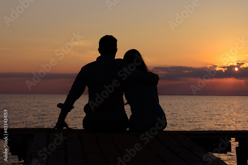 Two lovers on the pier by the sea. Silhouette of the heart. Love 