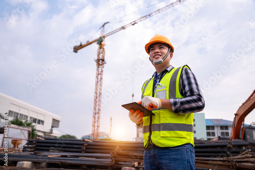 male construction engineer. Architect with a tablet computer at a construction site. Asian young man looking, building site place on background. Construction or building engineer concept