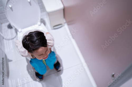 A boy is sitting on toilet with suffering.