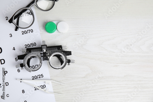 Different ophthalmologist tools on white wooden background, flat lay. Space for text photo