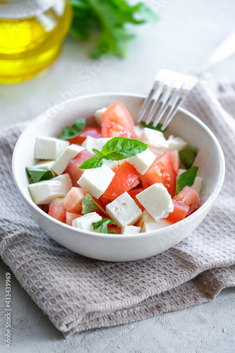 Italian caprese salad with sliced tomatoes  mozzarella  basil  olive oil on a light background. 