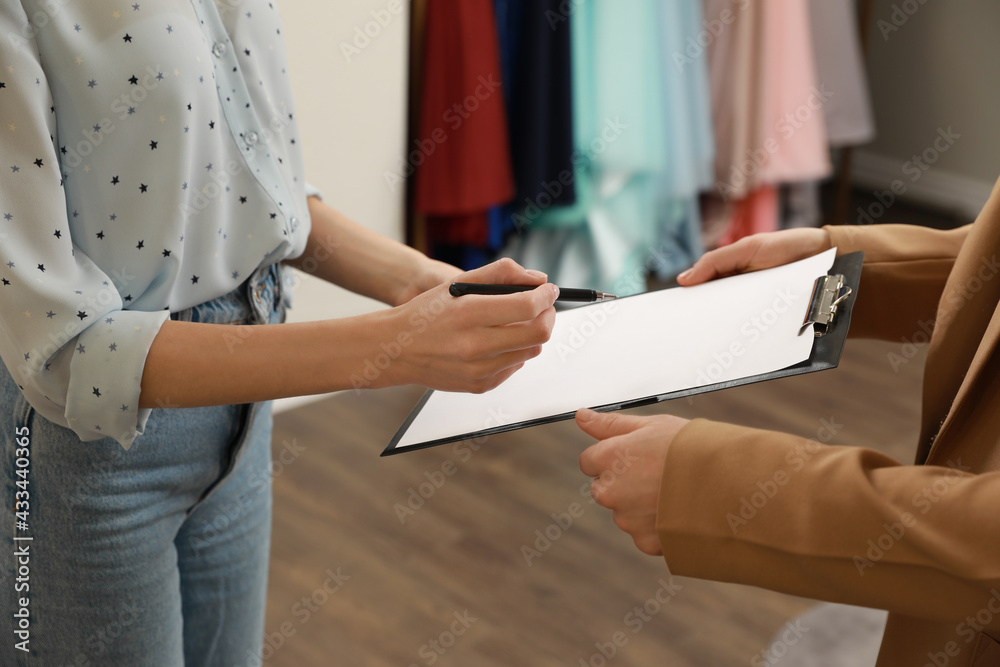 Obraz premium Woman signing rental agreement in clothing salon, closeup