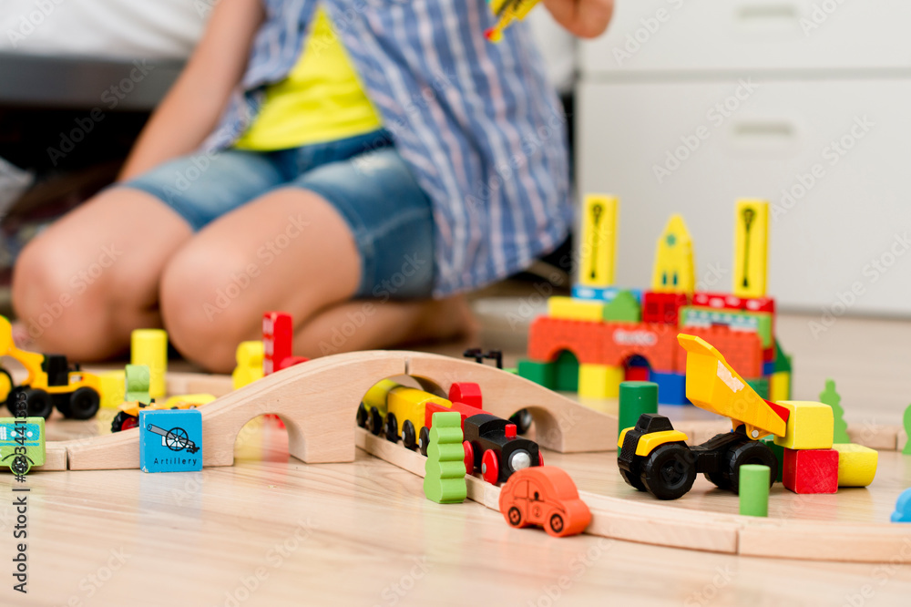 Boy plays with wooden toys. train rails, wooden block buildings.
