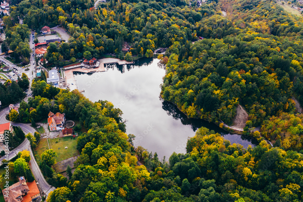 Colorful trees at the beginning of autumn seen from a drone with small lakes. 