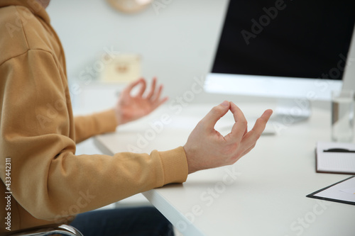 Man meditating at desk in light office, closeup