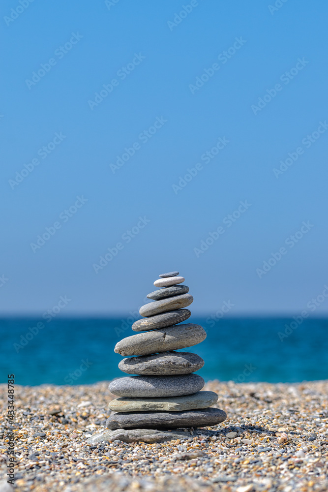 Fototapeta premium Tower of stones in the beach. Vertical. Selective focus