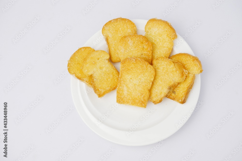 Crispy garlic bread on white plate on blue and yellow background Crispy garlic bread on white plate on blue and yellow background