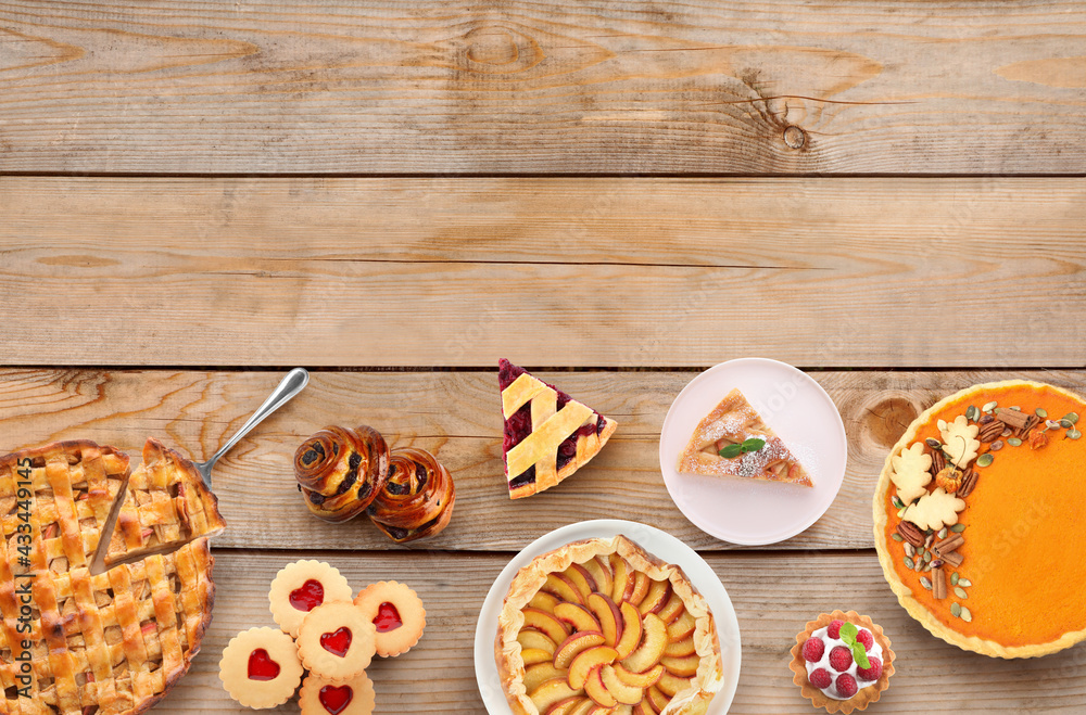 Many different delicious pies on wooden table, flat lay. Space for text