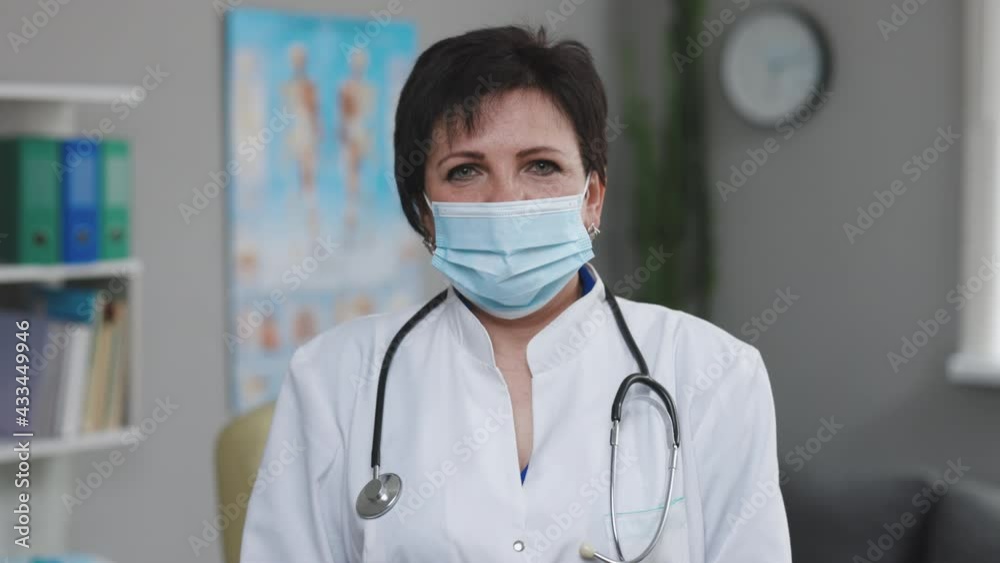 Portrait of Senior Family Medical Doctor in Face Mask. Successful Physician in White Lab Coat Looks at the Camera in Hospital Office. Covid-19 Pandemic Concept of Infectious Virus. Portrait of Senior Family Medical Doctor in Face Mask. Successful Physician in White Lab Coat Looks at the Camera in Hospital Office. Covid-19 Pandemic Concept of Infectious Virus.