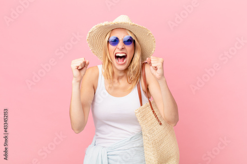 young blonde woman shouting aggressively with an angry expression. summer concept photo