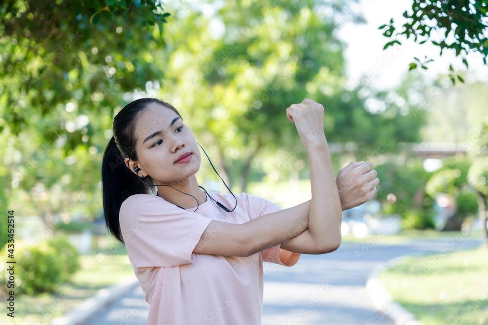 Happy young fitness woman doing stretch exercise outdoors in park, stretching her arms - tricep and shoulders for warming up before running or working out in morning. Healthy and Lifestyle Concept. Happy young fitness woman doing stretch exercise outdoors in park, stretching her arms - tricep and shoulders for warming up before running or working out in morning. Healthy and Lifestyle Concept.