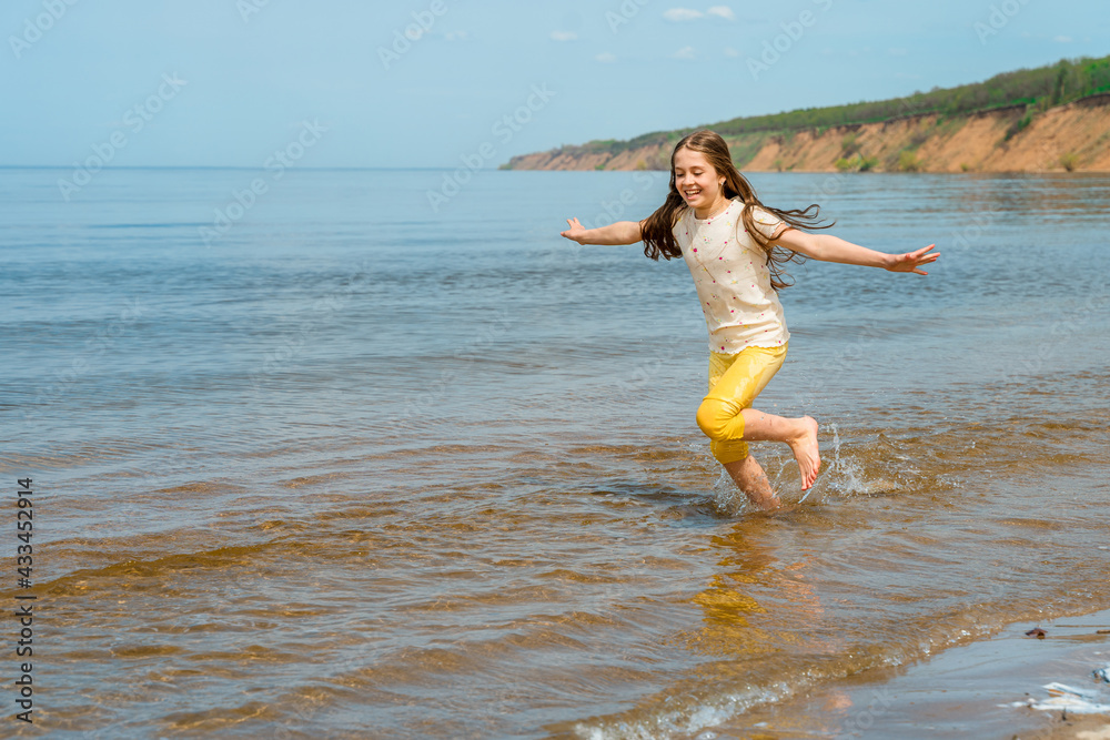 A little girl in bright yellow pants runs in the water and frolics on the beach A little girl in bright yellow pants runs in the water and frolics on the beach
