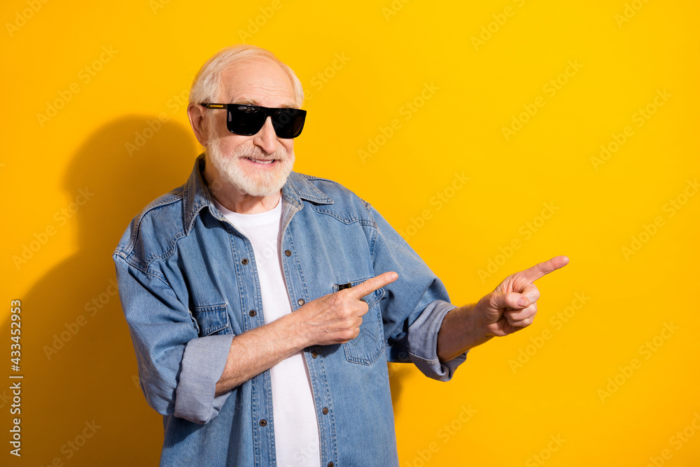 Photo of happy good mood funky funny grandfather in sunglass advertising product isolated on yellow color background Photo of happy good mood funky funny grandfather in sunglass advertising product isolated on yellow color background
