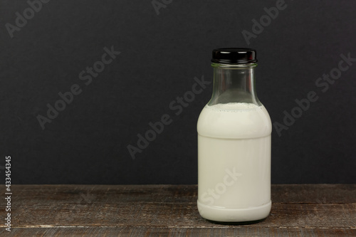 Milk in bottle on wooden table and black background.